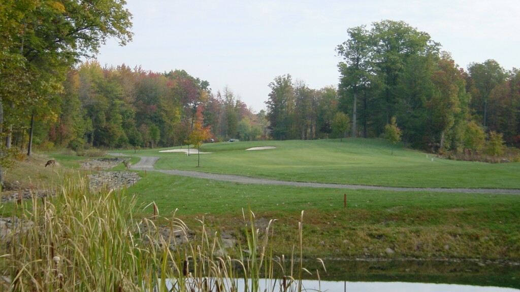 View of golf course with trees and cart path